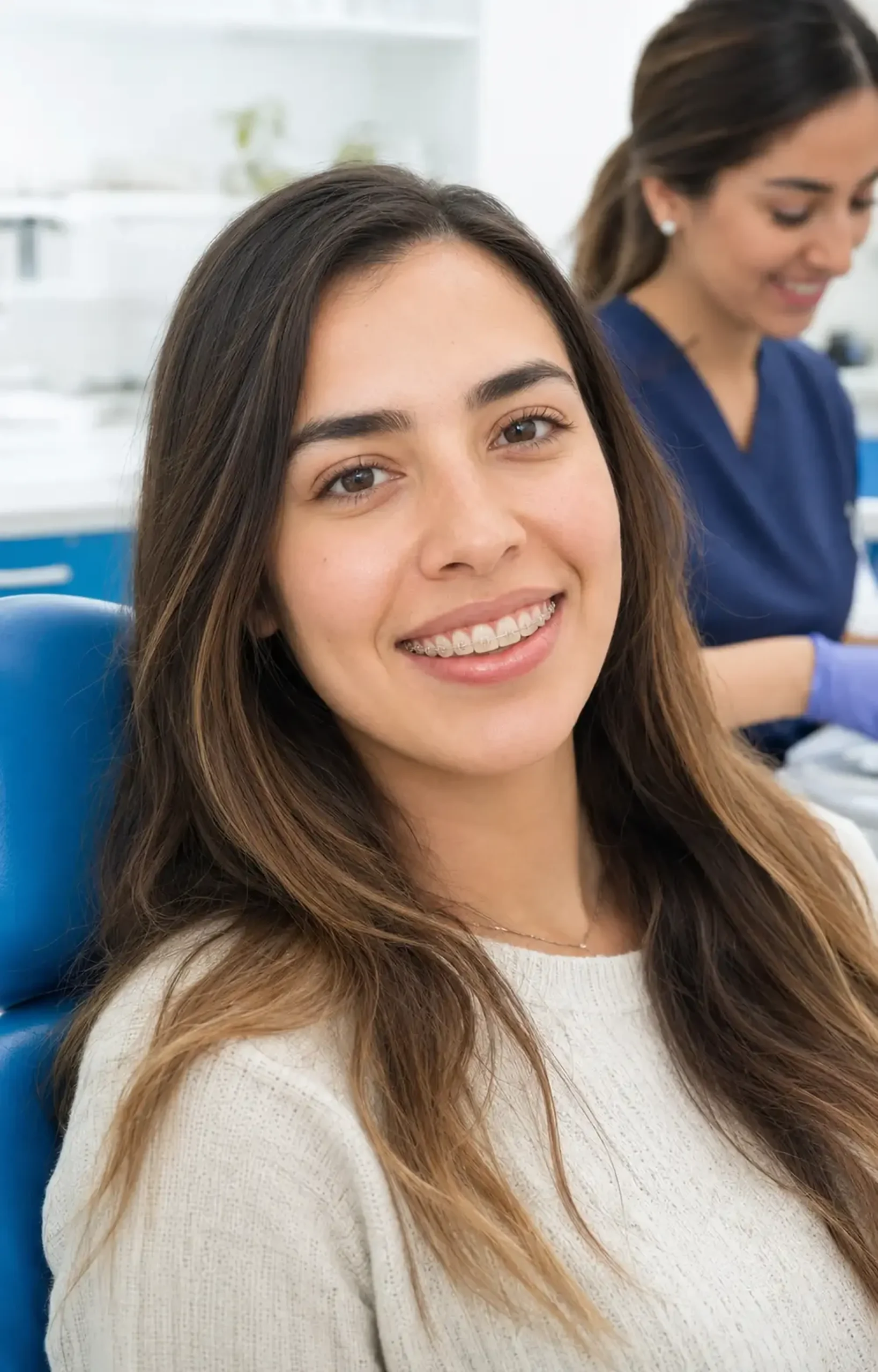 Paciente sonriendo con brackets cerámicos en una clínica dental
